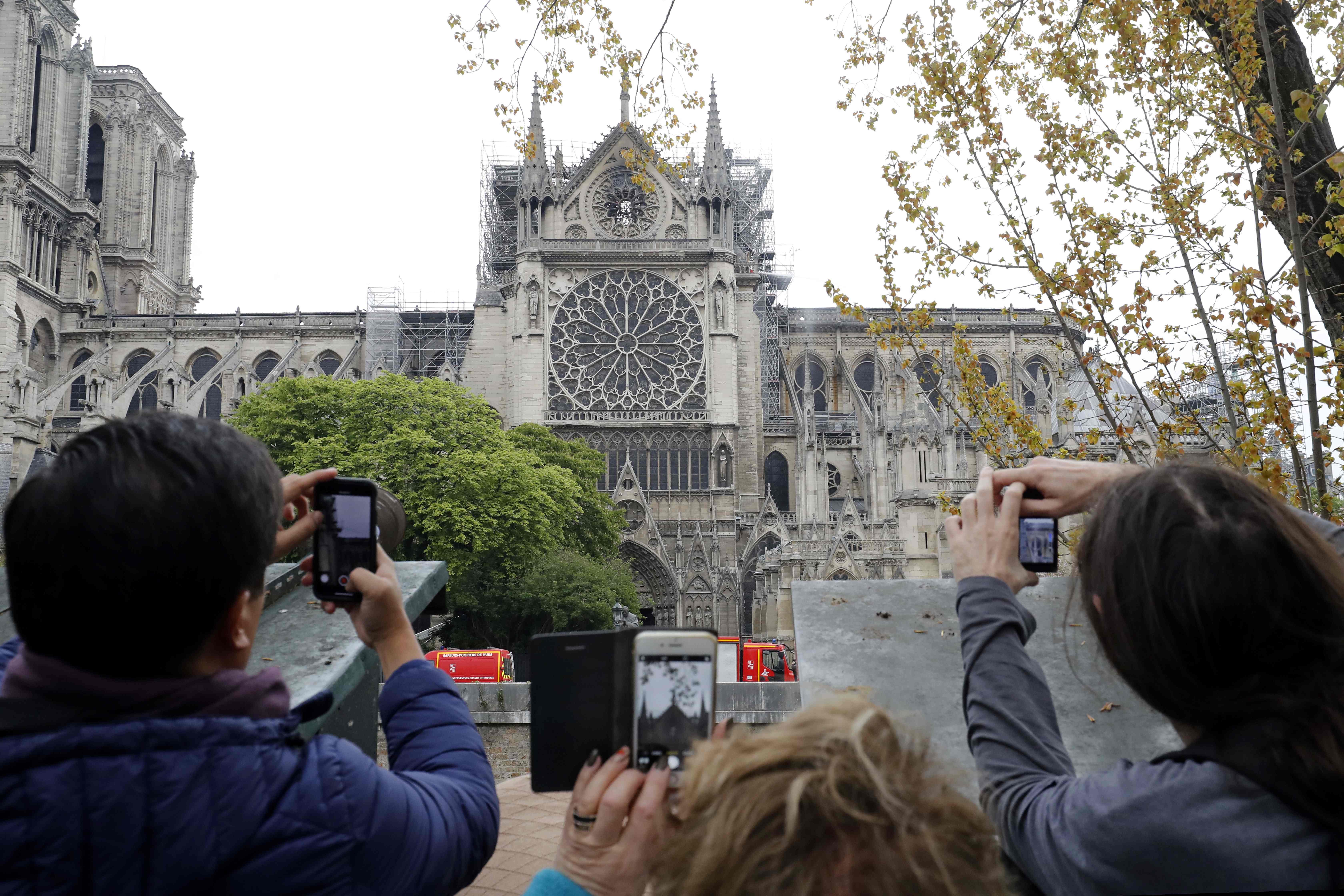 Turistas toman fotos a la Catedral de Notre Dame un día después del siniestro. (Foto Prensa Libre: AFP)