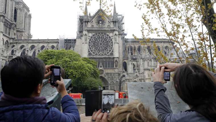 Turistas toman fotos a la Catedral de Notre Dame un día después del siniestro. (Foto Prensa Libre: AFP)