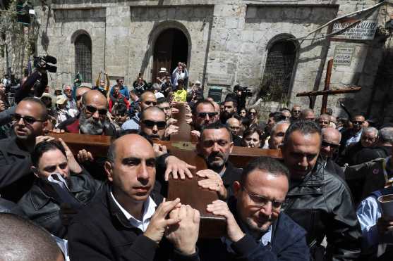 Los miembros de la parroquia católica palestina local llevan una cruz de madera a lo largo de la Vía Dolorosa (Camino del sufrimiento) en la Ciudad Vieja de Jerusalén durante la procesión del Viernes Santo. Foto Prensa Libre: AFP