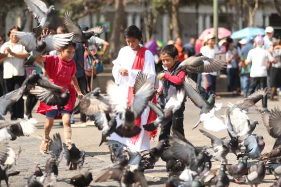 Niños simulan la epoca en que Jesús cargo la cruz y le dan alimentos a las aves en la Plaza de la Constitución.
