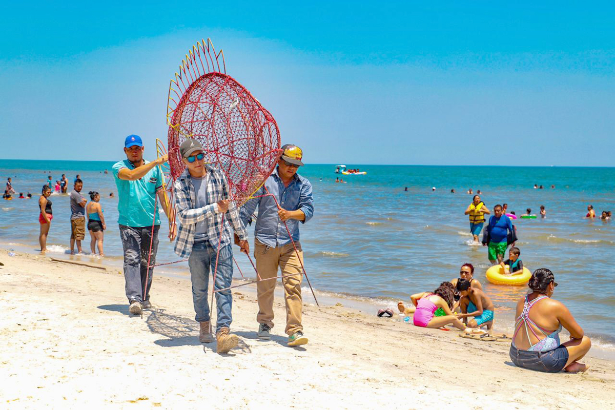 Personal de la comuna traslada una estructura metálica en forma de pez para instalarla como recolector de desechos de plástico en la playa Punta de Palma, Puerto Barrios, Izabal. (Foto Prensa Libre: Dony Stewart)