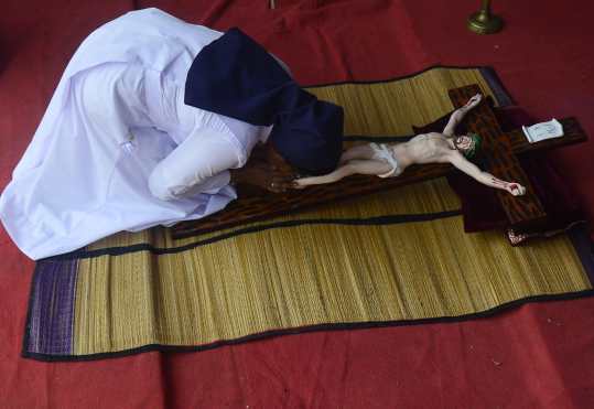 Una monja de Sri Lanka besa los pies de una efigie de Jesucristo en una cruz durante la misa del Viernes Santo en la aldea de Katukurunda en el distrito de Kalutara. Foto Prensa Libre: AFP
