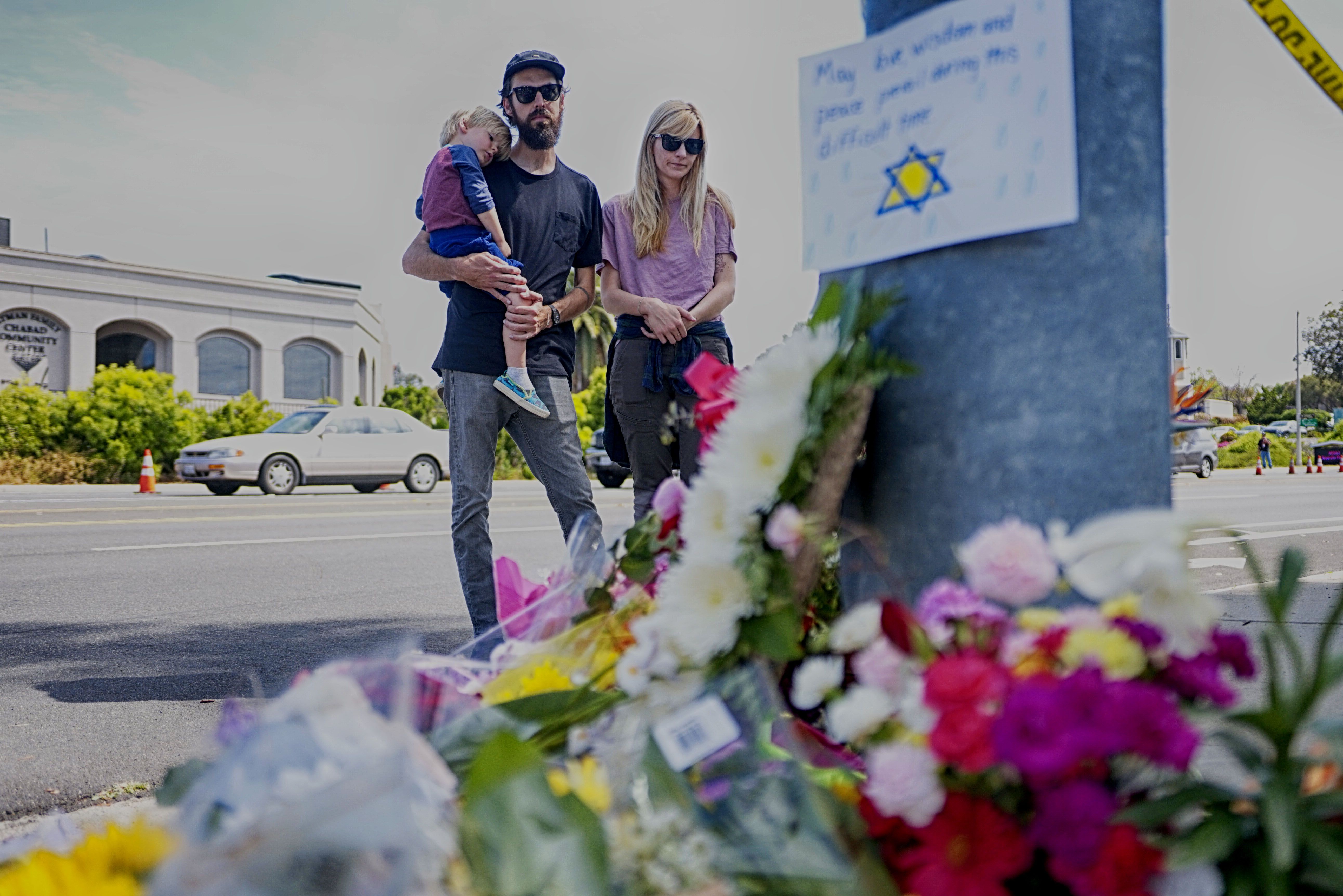 Una familia observa un memorial improvisado al otro lado de la calle de la Sinagoga Chabad de Poway, California, un día después de que un hombre armado disparara y matara a una e hiriera a tres. (Foto Prensa Libre: AFP).

