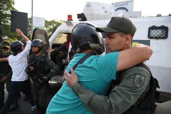 Un hombre venezolano abraza a un miembro de las fuerzas de seguridad  como símbolo de paz. Foto Prensa Libre: AFP