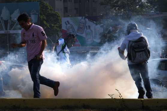 
Los venezolanos huyen de gas lacrimógeno durante las peleas con las fuerzas de seguridad en Caracas la mañana del 30 de abril. Foto Prensa Libre: AFP 