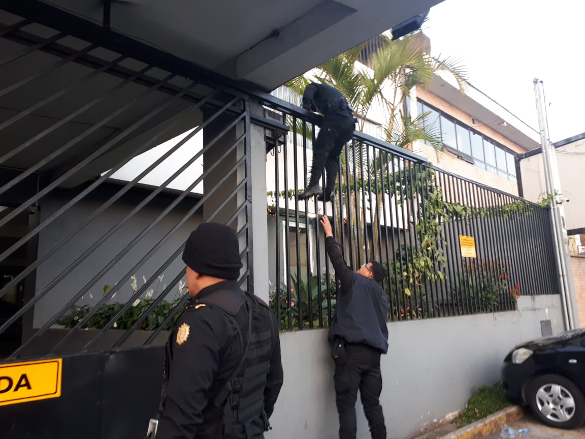 Un policía trepa en uno de los inmuebles en donde este viernes se llevó a cabo uno de los allanamientos en busca de los integrantes de al red de lavado. (Foto: PNC)