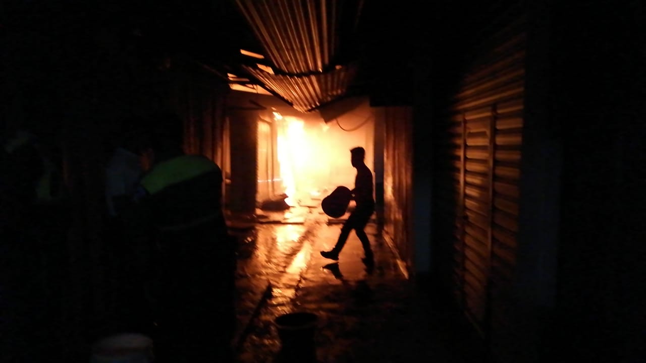 Vendedores intentan sofocar las llamas que destruye varios comercios en el mercado La Económica. (Foto Prensa Libre: Cortesía)