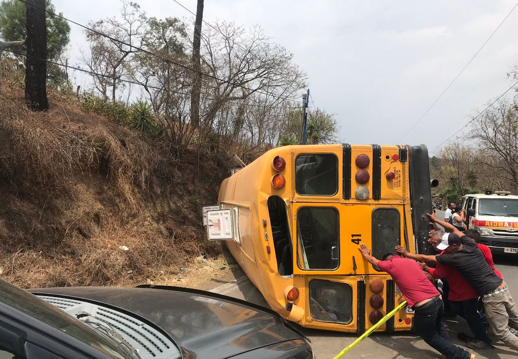 Pilotos y vecinos movilizan el autobús accidentado para liberar el paso en la ruta a San Raymundo. (Foto: Bomberos Municipales de Mixco)