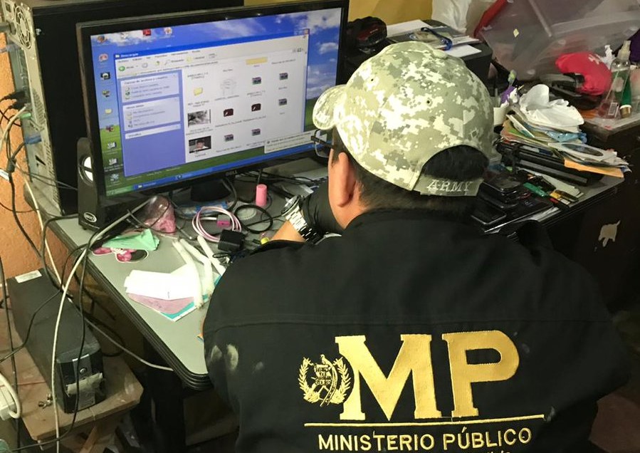 Un fiscal del Ministerio Público revisa la computadora de David Alejandro Pascual Argueta, alias Valdroxx, quien es señalado de producir y vender pornografía infantil. (Foto Prensa Libre: Cortesía) 
