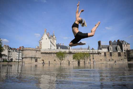 Una mujer baila en el Miroir d'Eau (Espejo de agua) frente al castillo de los Duques de Bretaña en Dantes, Francia. Foto Prensa Libre: AFP 
