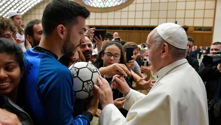El papa Francisco (d) firma un balón durante el evento "Il Calcio che Amiamo" (lit. El fútbol que amamos), organizado por el periódico deportivo italiano "La Gazzetta dello Sport". (Foto Prensa Libre: EFE)