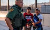 Border Patrol agent Frank Pino (L) is pictured with two migrants who presented themselves to the Border Patrol in El Paso, Texas on May 16, 2019. - "It's heart breaking, you know, I'm a father. I have two children. These guys out here, they are here with their kids," Pino said, "I kind of put myself in their position, and you know, would I do the same thing they're doing? Escaping violence or fleeing their countries, it's a hard decision, but I took an oath as a Border Patrol agent, my main priority is protecting this border, protecting this fence, and making sure that we identify for the security of my community where I live in El Paso, Texas. That's important to me." About 1,100 migrants from Central America and other countries are crossing into the El Paso border sector each day. Pino, public information officer for the Border Patrol, says that Border Patrol resources and personel are being stretched by the ongoing migrant crisis, and that the real targets of the Border Patrol are slipping through the cracks. (Photo by Paul Ratje / AFP)