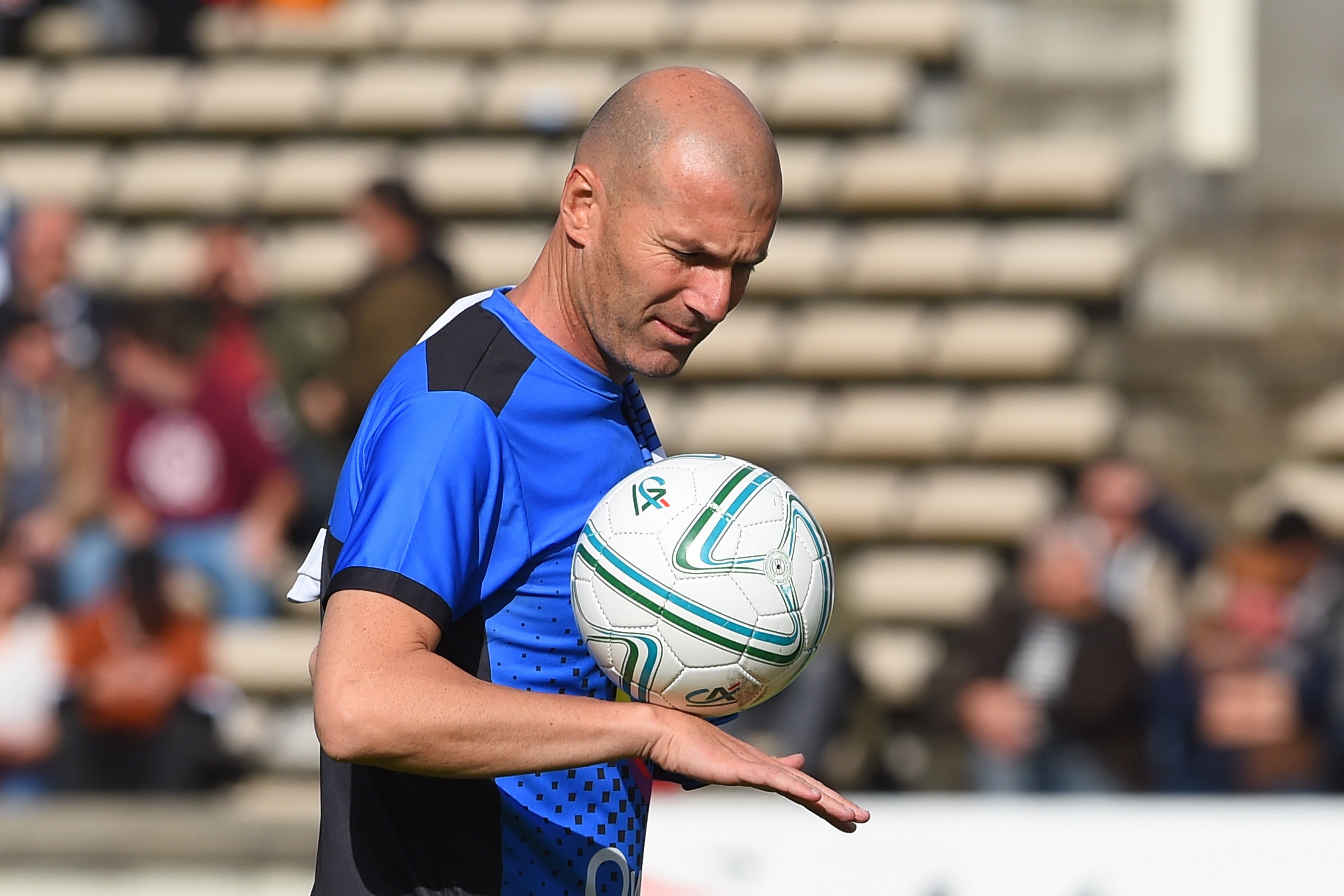 Real Madrid French coach Zinedine Zidane plays with the ball prior to a friendly football and rugby union match between former French football stars and former French rugby players. (Photo by NICOLAS TUCAT / AFP)