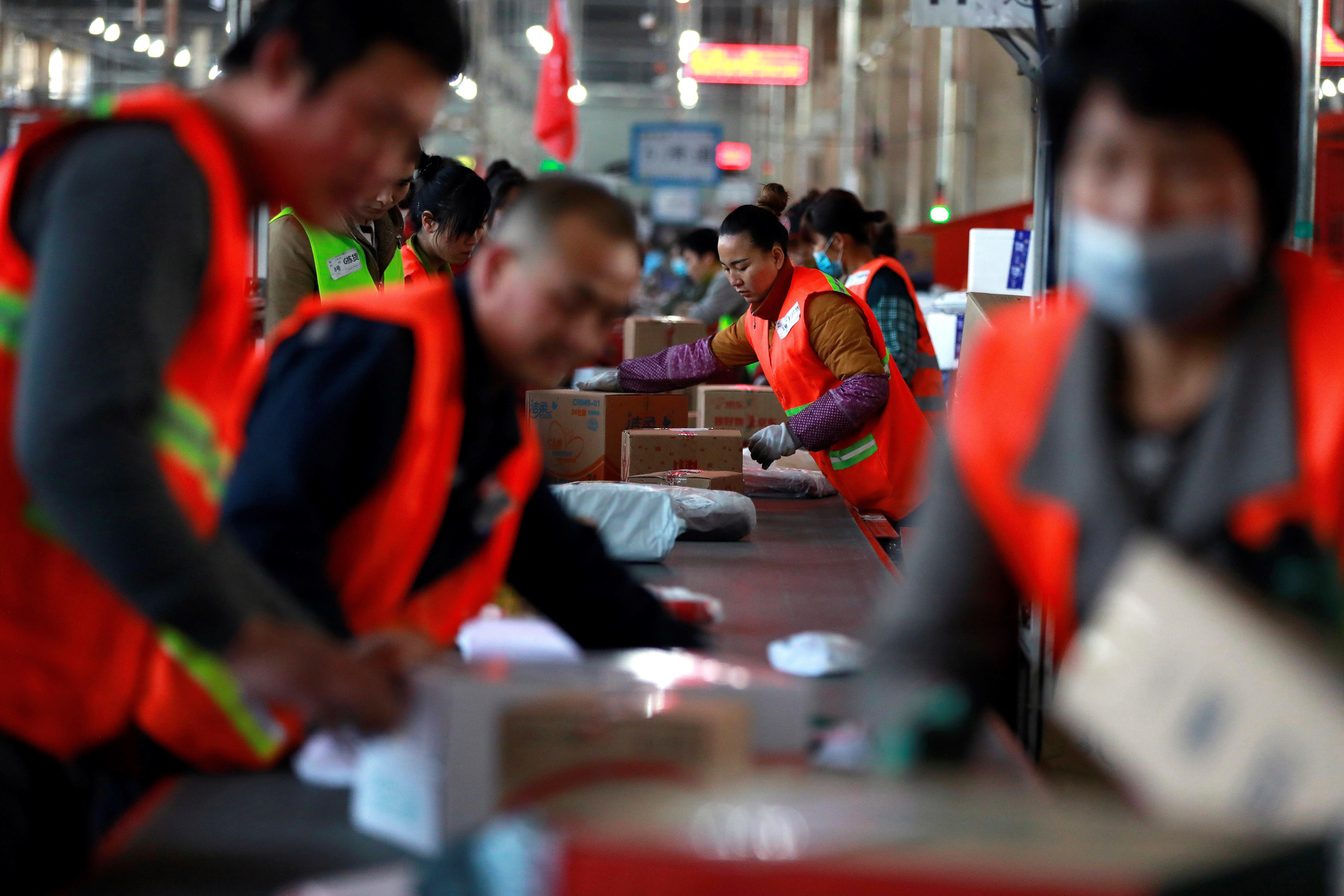 Empleados clasifican paquetes en una planta de reparto exprés durante el Día los Solteros en Pekín, China. (Foto Prensa Libre: EFE)