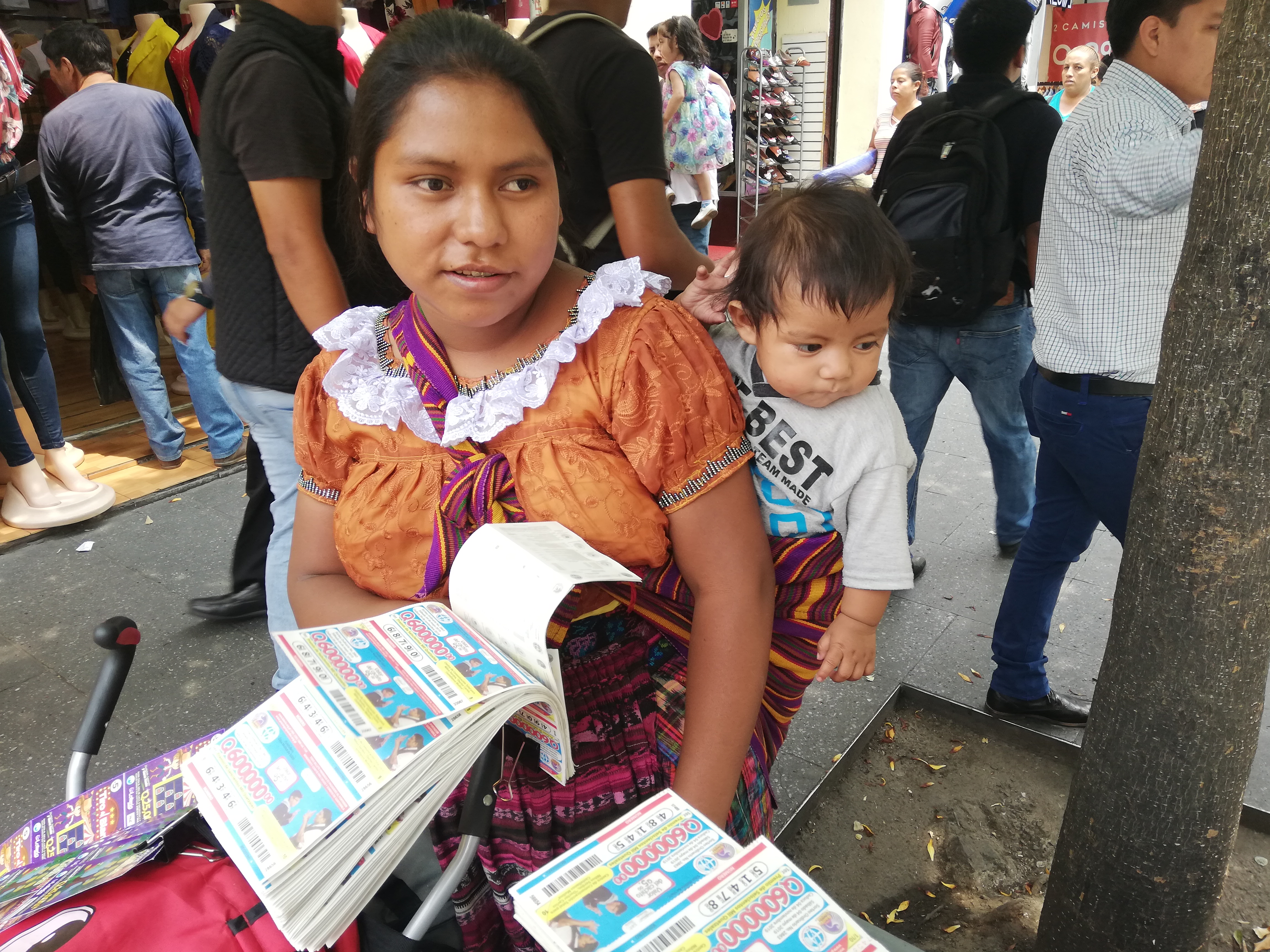Juana Us ofrece billetes de lotería junto a su hijo Baltazar Elías, de 7 meses. (Foto Prensa Libre: Oscar Fernando García). 