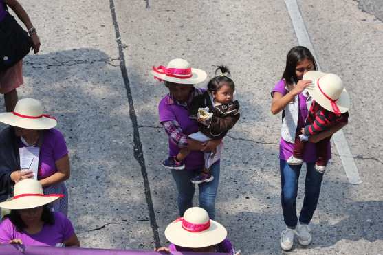 Mujeres trabajadoras participan en la marcha con sus hijos en brazos.