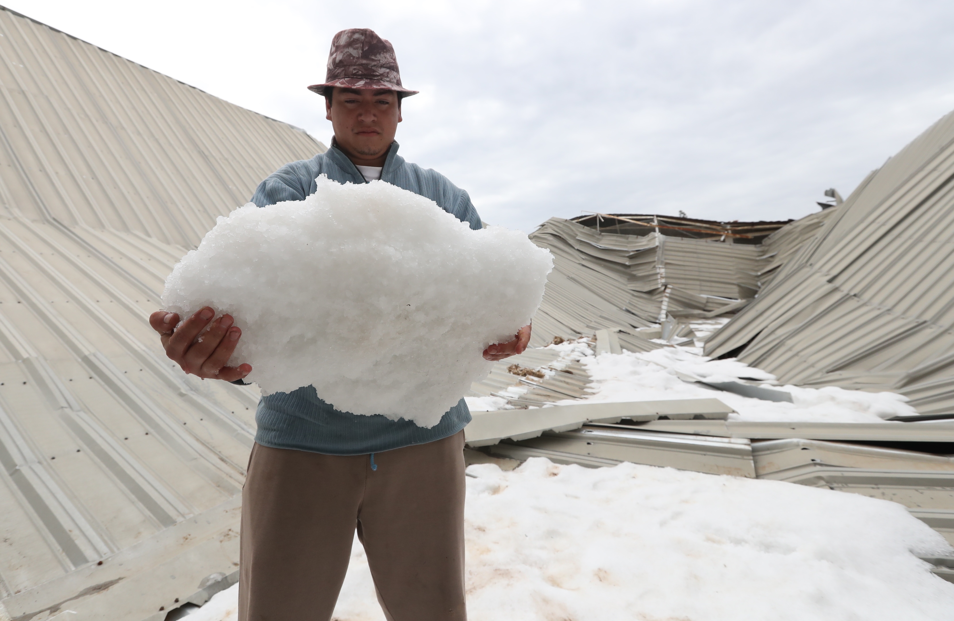 Un vecinos de Sija sostiene un bloque de hielo que se formó del granizo que derrumbó el techo de un cancha de futbol. (Foto Prensa Libre: Mynor Toc)