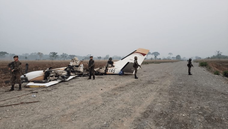 Elementos del Ejército custodian los restos de la avioneta, aunque minutos después fueron expulsados por comunitarios de la aldea Siete Cerros. (Foto Prensa Libre: Cortesía)