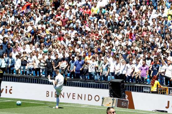 Luka Jovic con la camiseta del Real Madrid en el cesped del estadio Santiago Bernabeu donde acudieron numerosos aficionados tras su presentación como nuevo jugador del club blanco.  (Foto Prensa Libre: EFE)