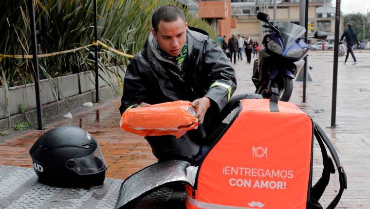 Un mensajero en bicicleta que trabaja para la empresa colombiana de entrega en línea "Rappi", organiza un pedido en Bogotá,. (Foto Prensa Libre: AFP)