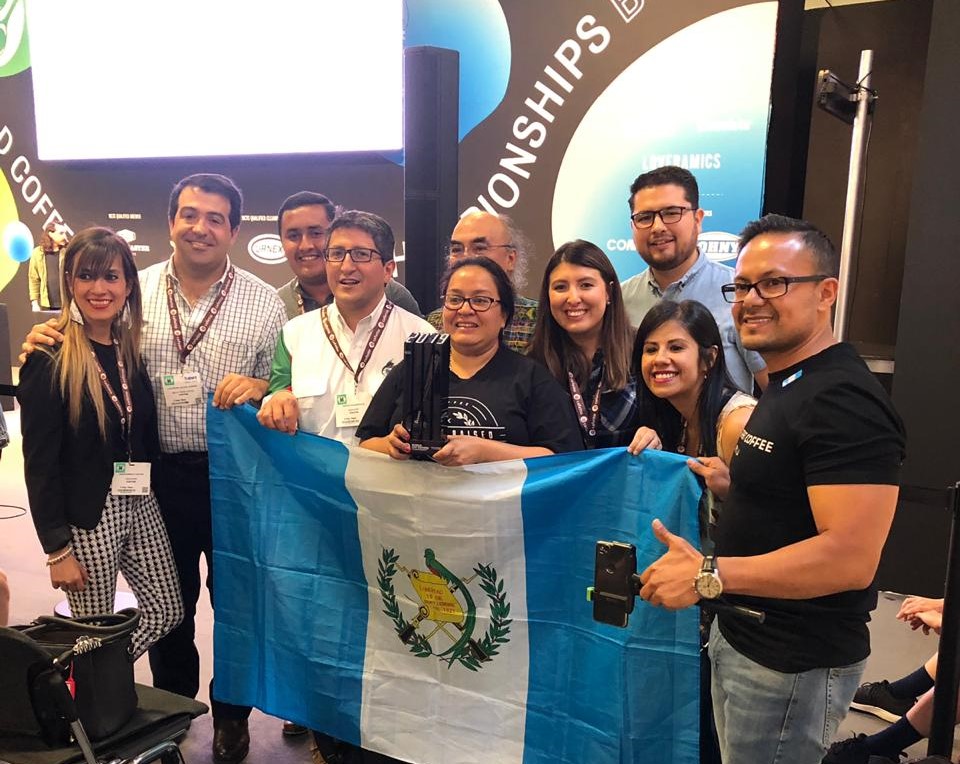 Dulce Barrera, tres veces campeona de catación en Guatemala, quedó en cuarto lugar en Copa Mundial de Café que se llevó a cabo en Alemania, la acompañan amigos y fundadores del Beneficio Buena Vista, donde labora. (Foto Prensa Libre: cortesía)