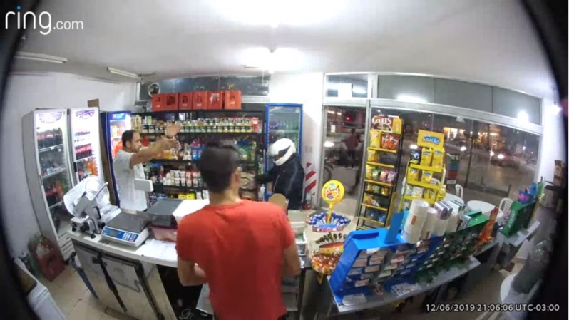 Imagen captada por la cámara de la tienda, en la que se observa al asaltante, con casco blanco, momentos antes de dispararse en la ingle. (Foto del sitio www.t13.cl)