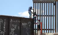 Un grupo de personas tratan de saltar el muro para entrar a territorio estadounidense este lunes, desde el puente negro, en la línea fronteriza de Ciudad Juárez. (Foto Prensa Libre EFE)