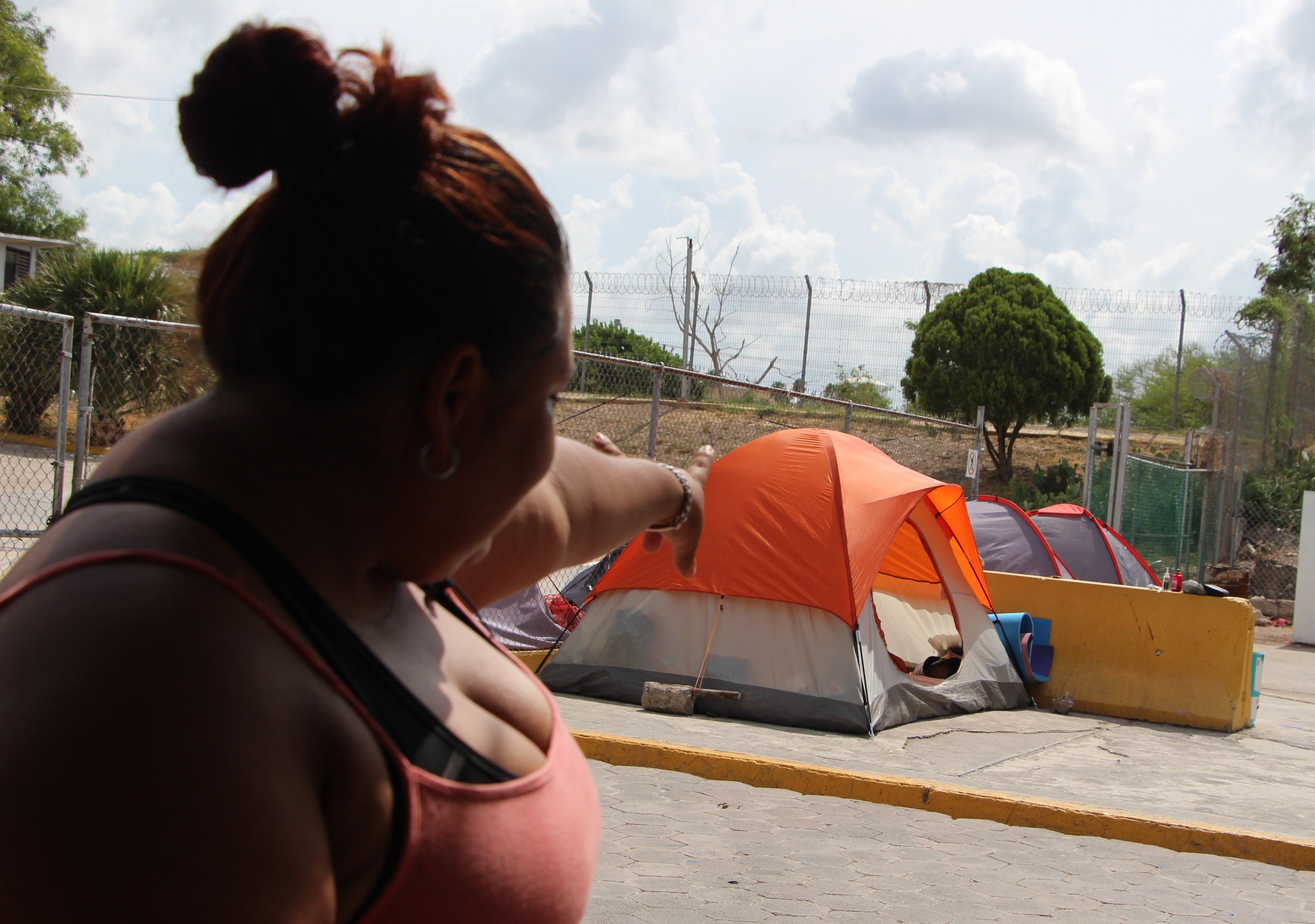 La migrante hondureña Melissa Aldana muestra las tiendas de campaña donde esperan algunos migrantes, en Matamoros, México. (Foto Prensa Libre: EFE).
