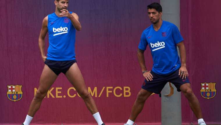 Los jugadores del FC Barcelona Luis Suárez y Gerard Piqué, durante el entrenamiento de pretemporada realizado este miércoles. (Foto Prensa Libre: EFE).