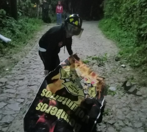 Bombero cubre el cadáver del motorista que murió en San José Pinula. (Foto Prensa Libre: @BVoluntariosGT).