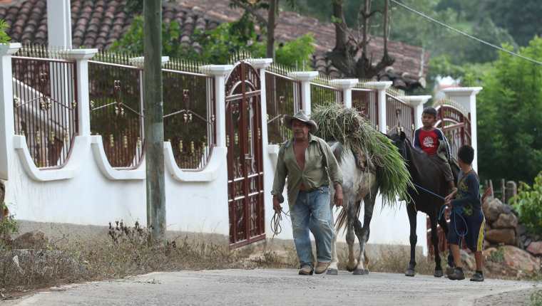 Un hombre camina por una calle de la aldea El Quebracho, frente a un vivienda inhabitada, como muchas en la comunidad de las cuales las familias se fueron a EE. UU. (Foto Prensa Libre: Esbin García)