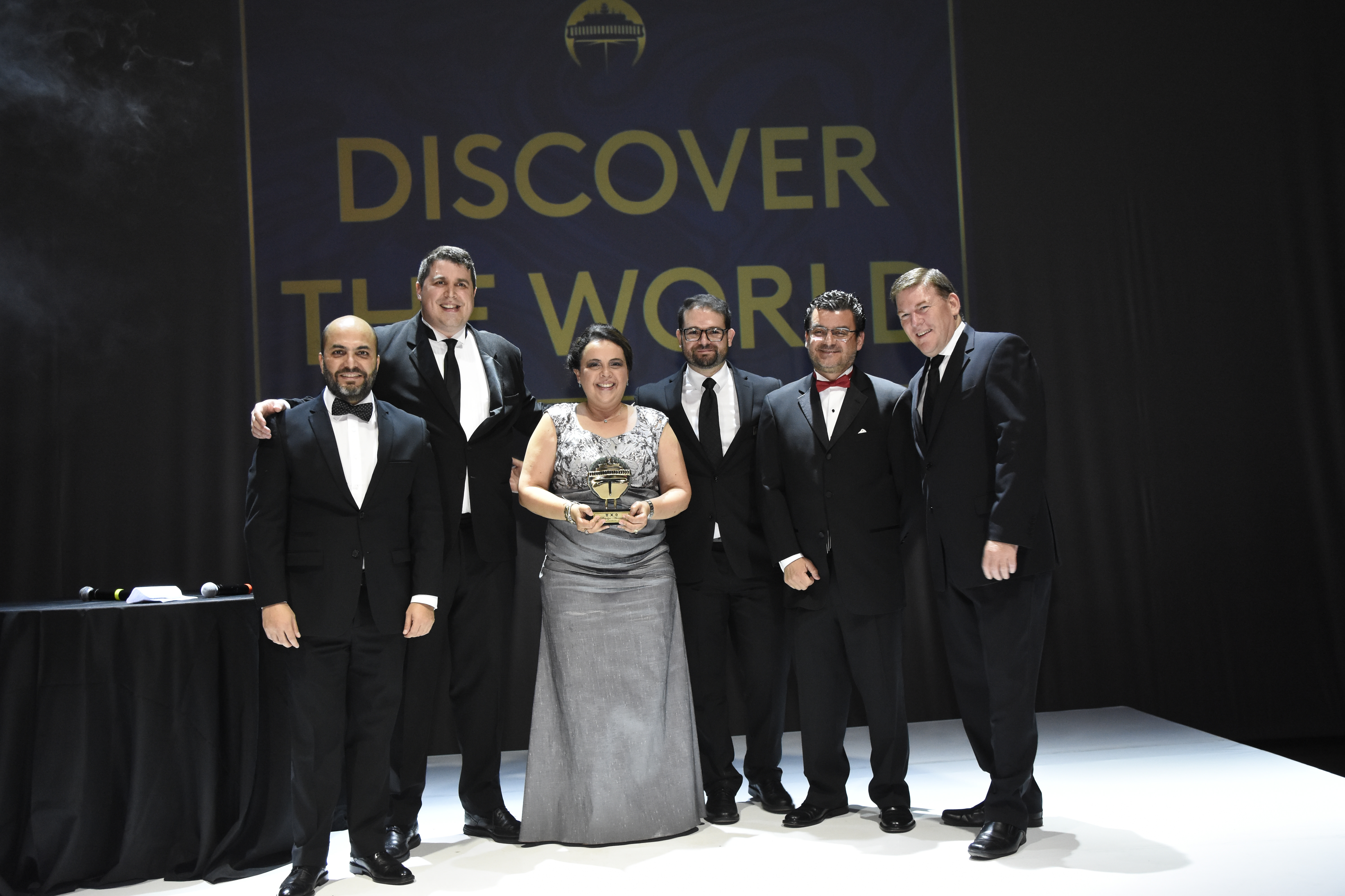 Mónica Girón de Ufer, directora de Discover the World Guatemala, muestra su reconocimiento con ejecutivos de Royal Caribbean.