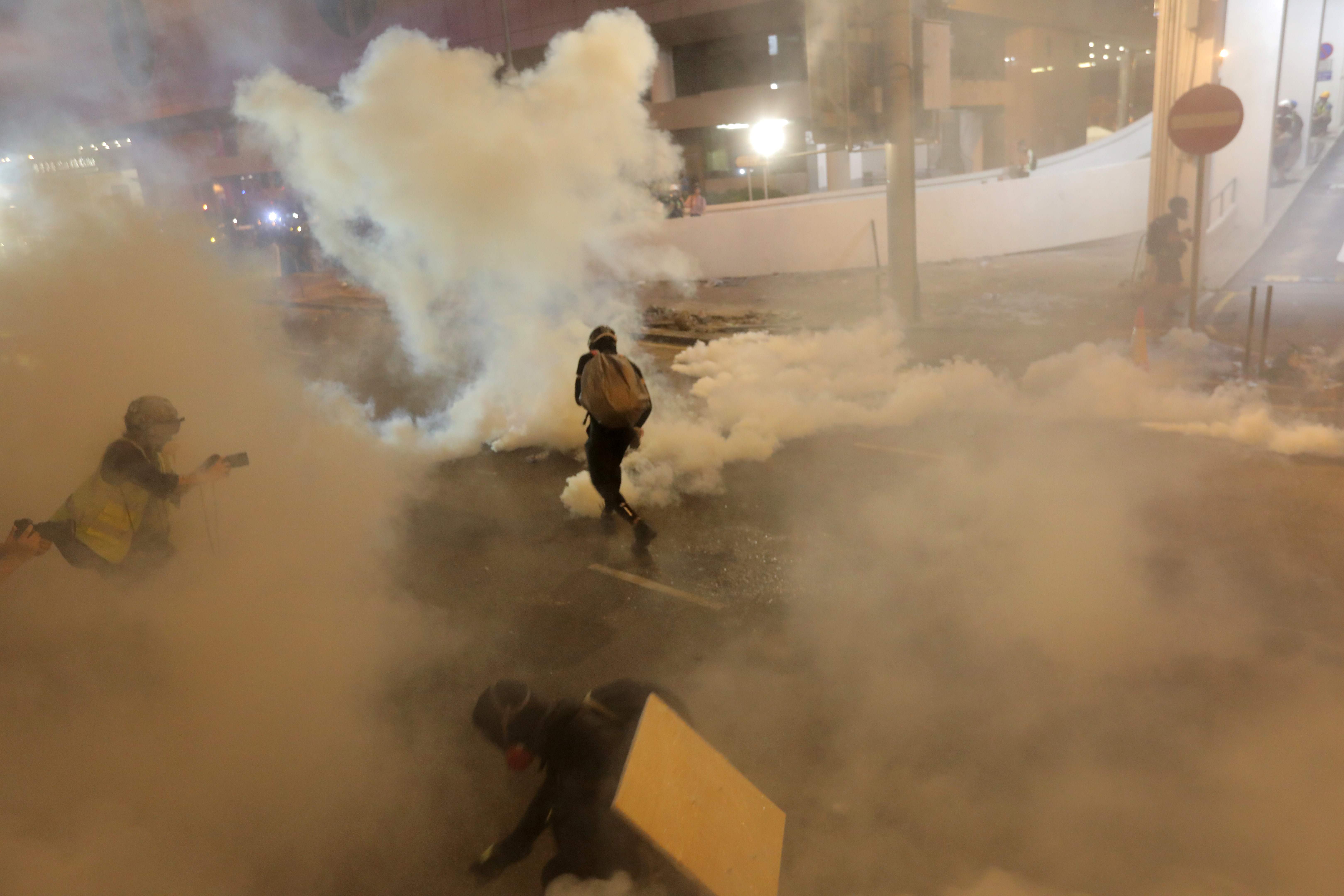 Manifestantes en Hong Kong huyen del gas lacrimógeno disparado por la Policía después de una marcha contra proyecto de ley de extradición a China. (Foto Prensa Libre: AFP). 