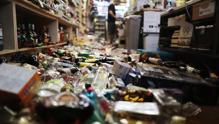 Un trabajador comienza a ordenar una tienda de abarrotes que colapsó con el sismo del pasado viernes. (Foto Prensa Libre: AFP)