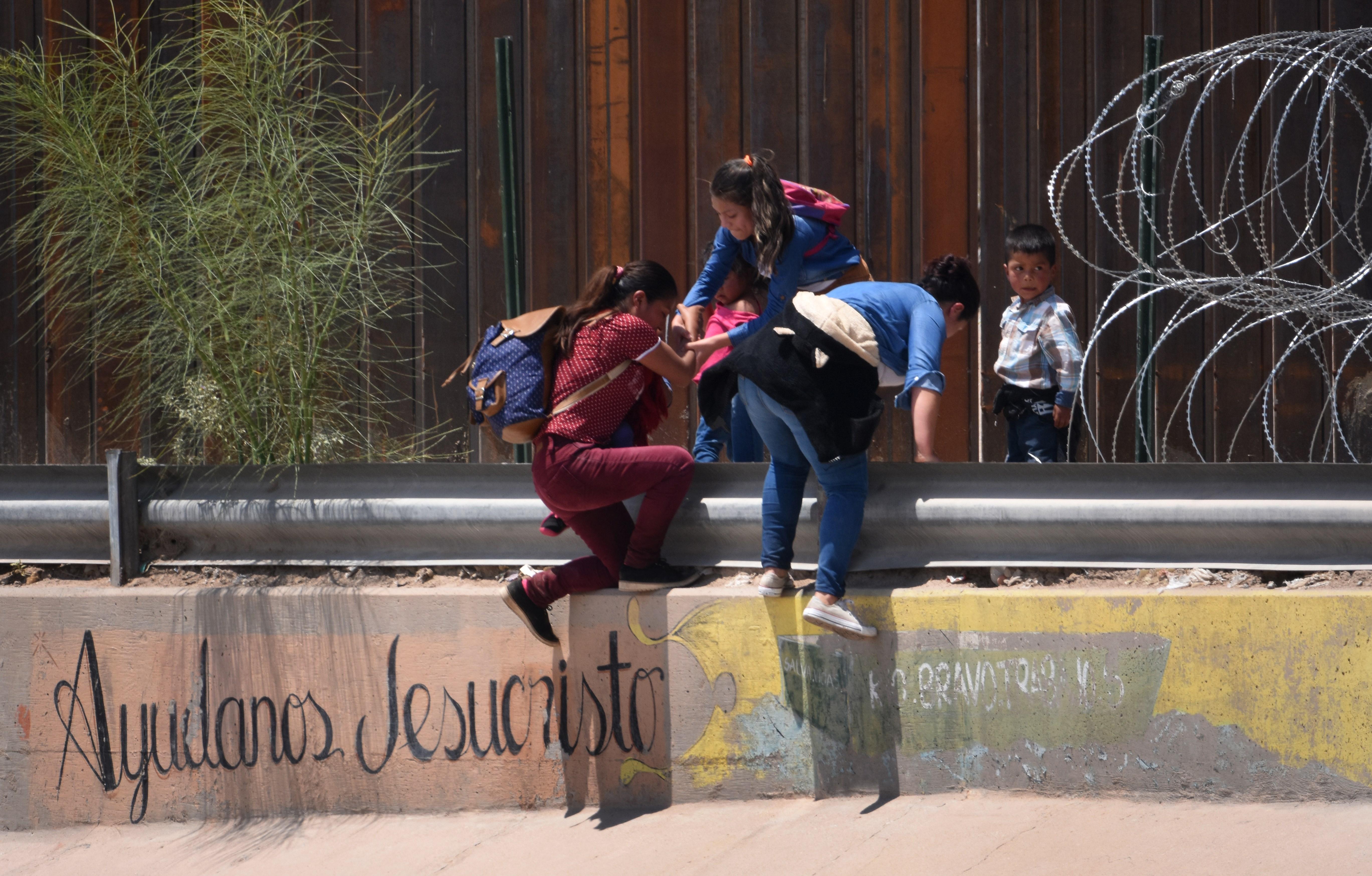 Una madre migrante junto con sus hijos brincan la barda fronteriza que separa a Estados Unido y México, cercano al puente internacional de Santa Fe, en Ciudad Juárez, en el estado de Chihuahua, México. (Foto Prensa Libre: EFE)
