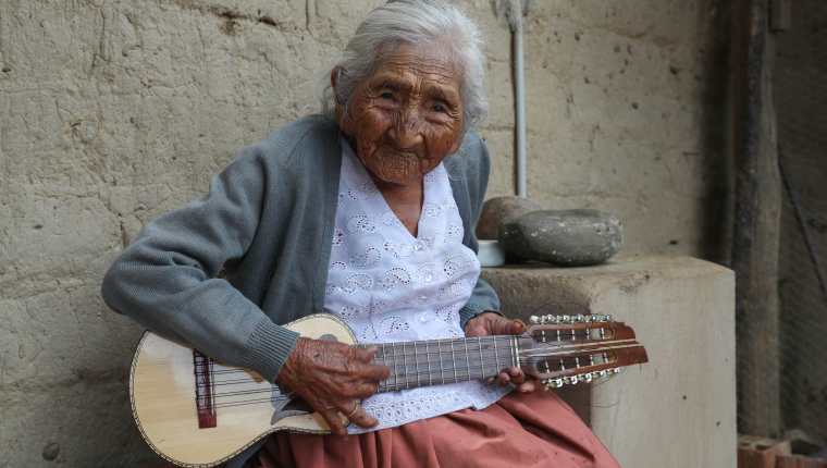 En la fotografía, Julia Flores Qolque, más conocida en Bolivia cómo "Mamá Julia", mientras toca su charango, en su casa de la localidad de Sacaba, a 18 kilómetros de la ciudad de Cochabamba (Bolivia). Mamá Julia, considerada la más longeva de su país, murió este sábado en la mañana a dos meses de cumplir los 119 años de vida. (Foto Prensa Libre: EFE)