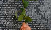 A woman puts a flower near the name a relative at the monument to the people who disappeared during the civil war commemorating the International Day of the Disappeared, at Cuscatlan Park in San Salvador, on August 30, 2019. - About 8000 people went missing during El Salvador's 1979-1992 civil war between his leftist guerrillas and US-backed rightwing governments (Photo by Oscar Rivera / AFP)