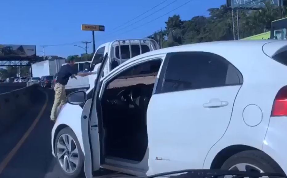 El automovilista intenta abrir la puerta del camión con el que tuvo problemas. 