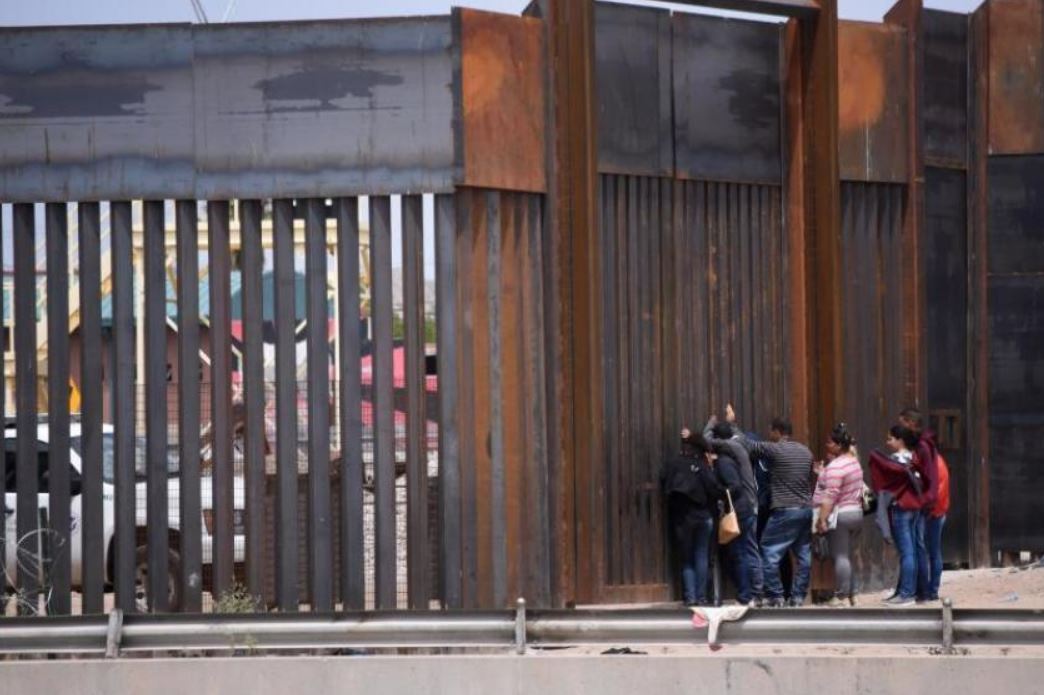 Migrantes centroamericanos se asoman en por el muro fronterizo, para entregarse a las autoridades migratoria estadounidenses, en el tramo de Puente Nuevo, en Ciudad Juárez (México). (Foto Prensa Libre: EFE)