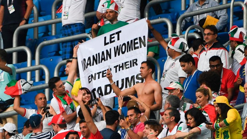En Irán, las mujeres no pueden entrar a los estadios de fútbol desde la revolución islámica, en 1979. En la foto, varias personas sostienen una pancarta que dice "permitamos que las mujeres iraníes entren en sus estadios". GETTY IMAGES