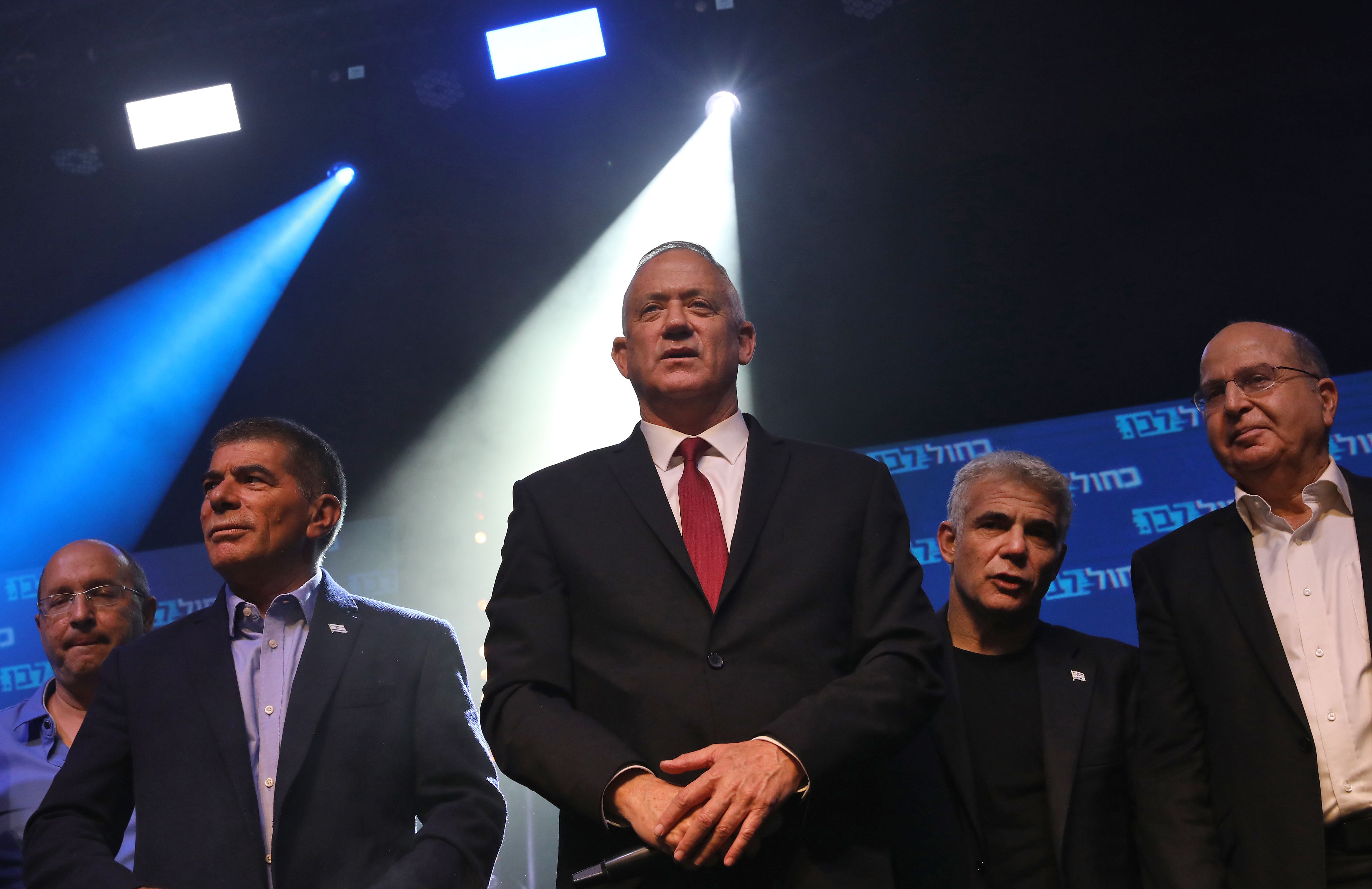 Independent Gabi Ashkenazi (2nd-L), Benny Gantz (C) of the Israel Resilience party, Yair Lapid (2nd-R) of the Yesh Atid party, and Moshe Yaalon (R) of the Telem party, leaders of the Blue and White (Kahol Lavan) political alliance, sing on stage after addressing supporters at the alliance's campaign headquarters in the Israeli coastal city of Tel Aviv early on September 18, 2019. - Benny Gantz, the main challenger to Israeli Prime Minister Benjamin Netanyahu in the country's general election, called for a broad unity government as exit surveys showed a tight race. "We will act to form a broad unity government that will express the will of the people," Gantz told supporters at a post-election rally in Tel Aviv. He however cautioned that he was waiting for final results. (Photo by GALI TIBBON / AFP)