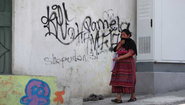 Una vecina camina frente a un grafitti pintado en una de las paredes de un inmueble del bulevar principal de Prados de Villa Hermosa. (Foto Prensa Libre: Érick Ávila) 