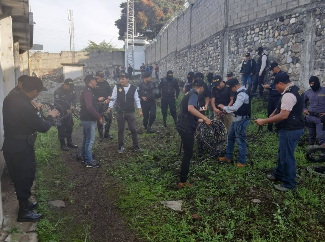 Investigadores enrollan el cable decomisado en los alrededores de la cárcel de El Boquerón, en Cuilapa, Santa Rosa. (Foto Prensa Libre: PNC). 

