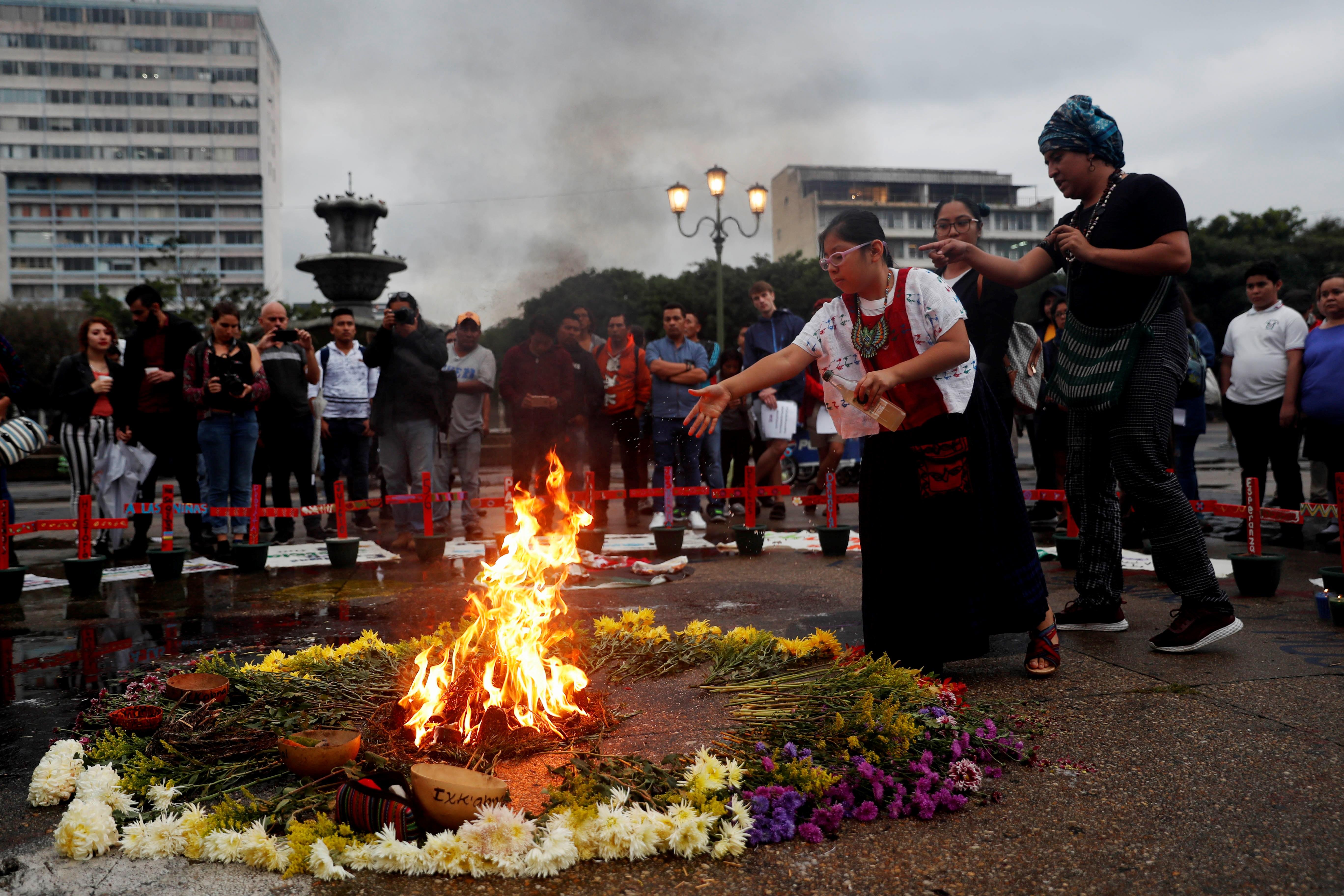Una niña aviva el fuego durante una ceremonia para reinstalar el altar en memoria de las 41 niñas y adolescentes que murieron quemadas en el Hogar Seguro. (Foto Prensa Libre: EFE)