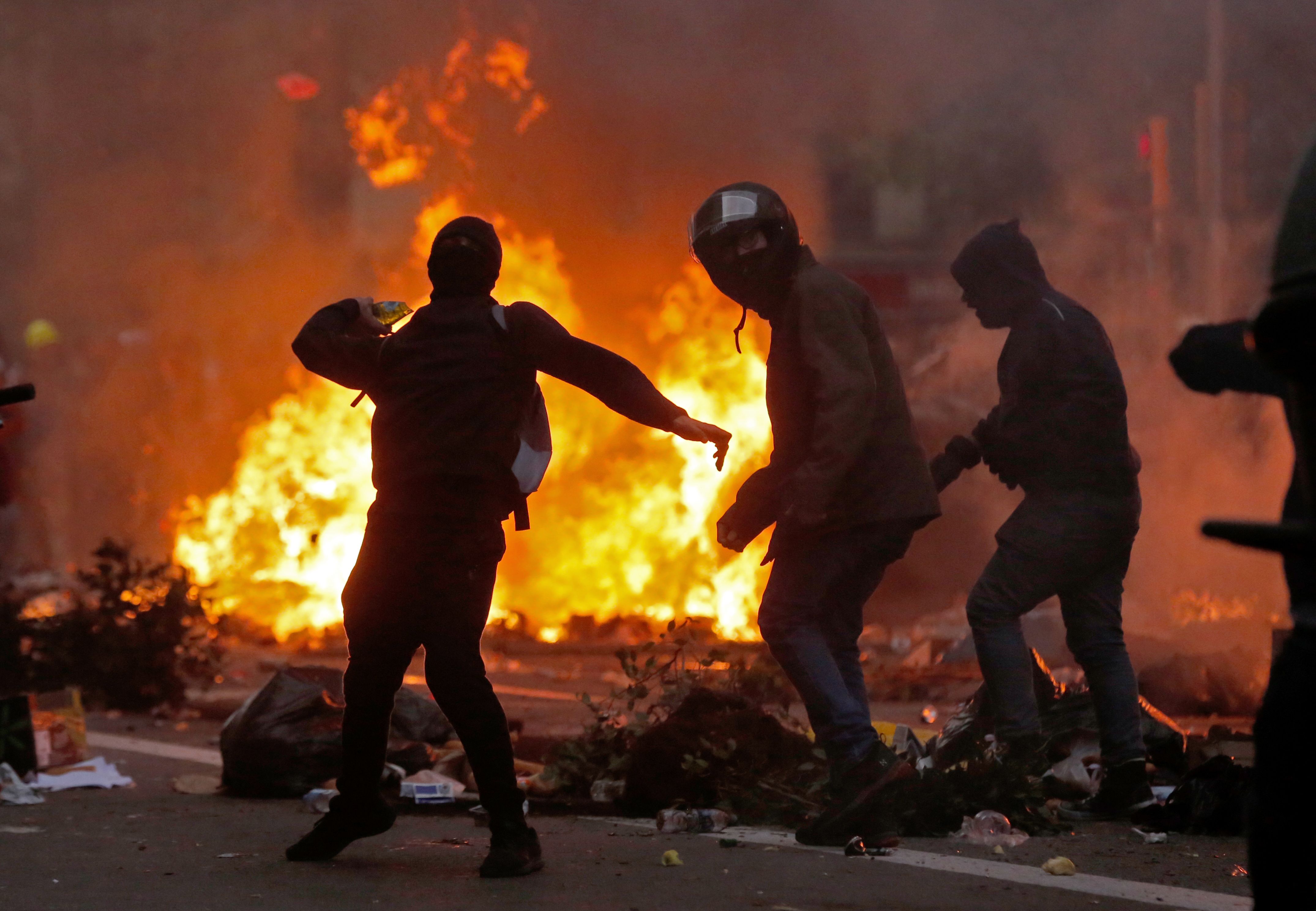 Los manifestantes arrojan objetos cerca de una barricada en llamas cerca de la sede de la Policía en Barcelona, ​​este 18 de octubre donde los separatistas convocaron una huelga general y una manifestación masiva. 
Foto: Prensa Libre: AFP
