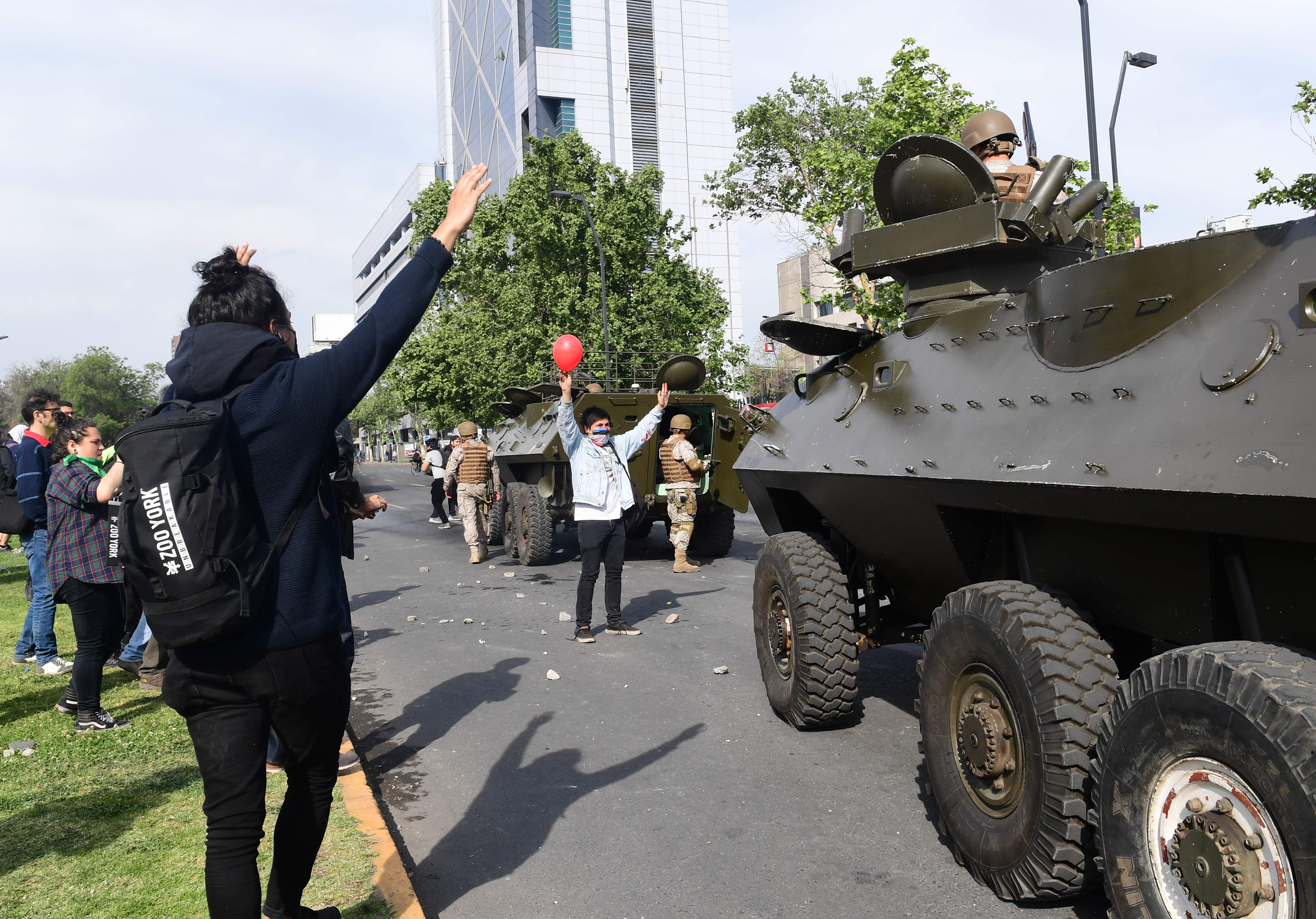 Los manifestantes se paran frente a vehículos militares en Santiago, el 19 de octubre de 2019. (Foto Prensa Libre: AFP).