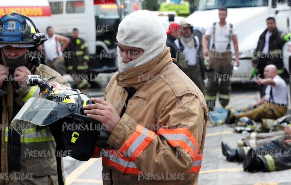 Uno de los bomberos revisa su equipo de protección luego del incendio. (Foto Prensa Libre: Esbin García)