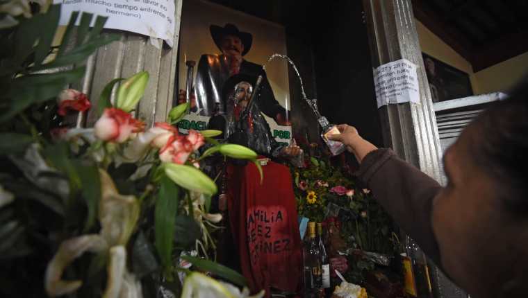 
La imagen de madera de San Simón es cubierta con un plástico transparente durante su celebración. (Foto Prensa Libre: AFP)
