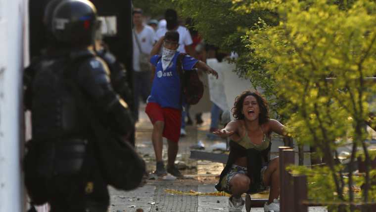 Una mujer grita entre un manifestante que enfrenta a la policía durante el desarrollo de las protestas y movilizaciones por el denominado Paro Nacional. (Foto Prensa Libre: EFE)