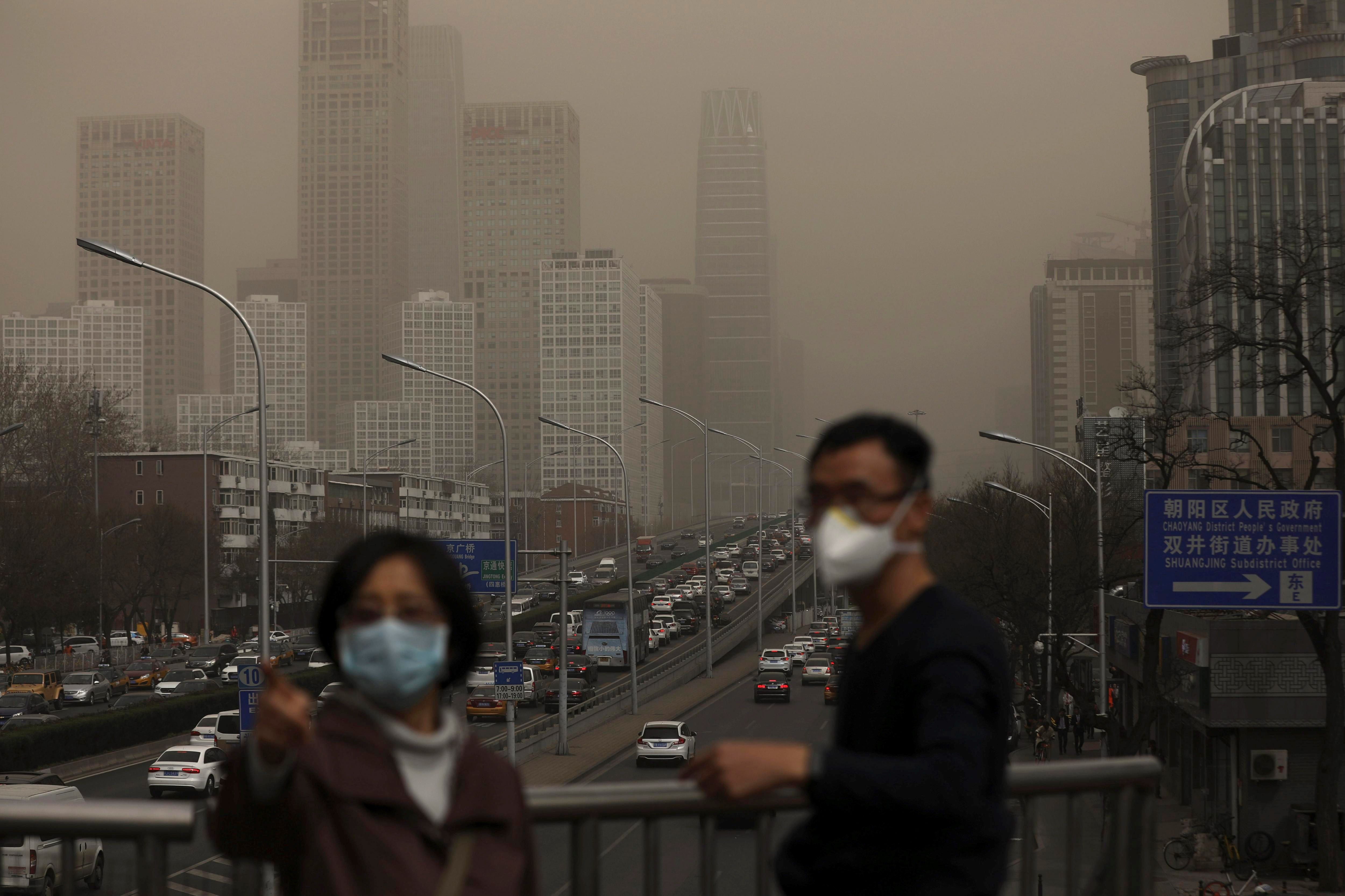 Un hombre y una mujer se protegen con máscaras de la nube de contaminación que cubre la ciudad de Pekín. (Foto Prensa Libre: EFE)